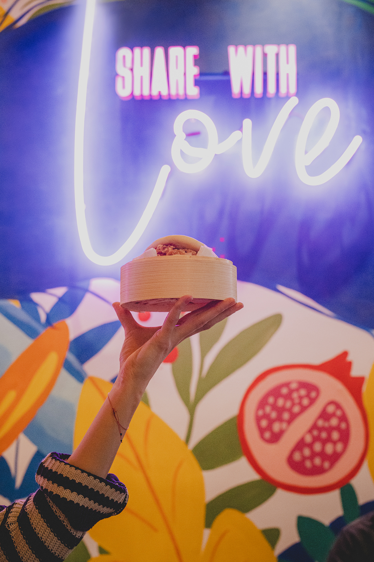 hand holding Bao bun on neon text "share with love"